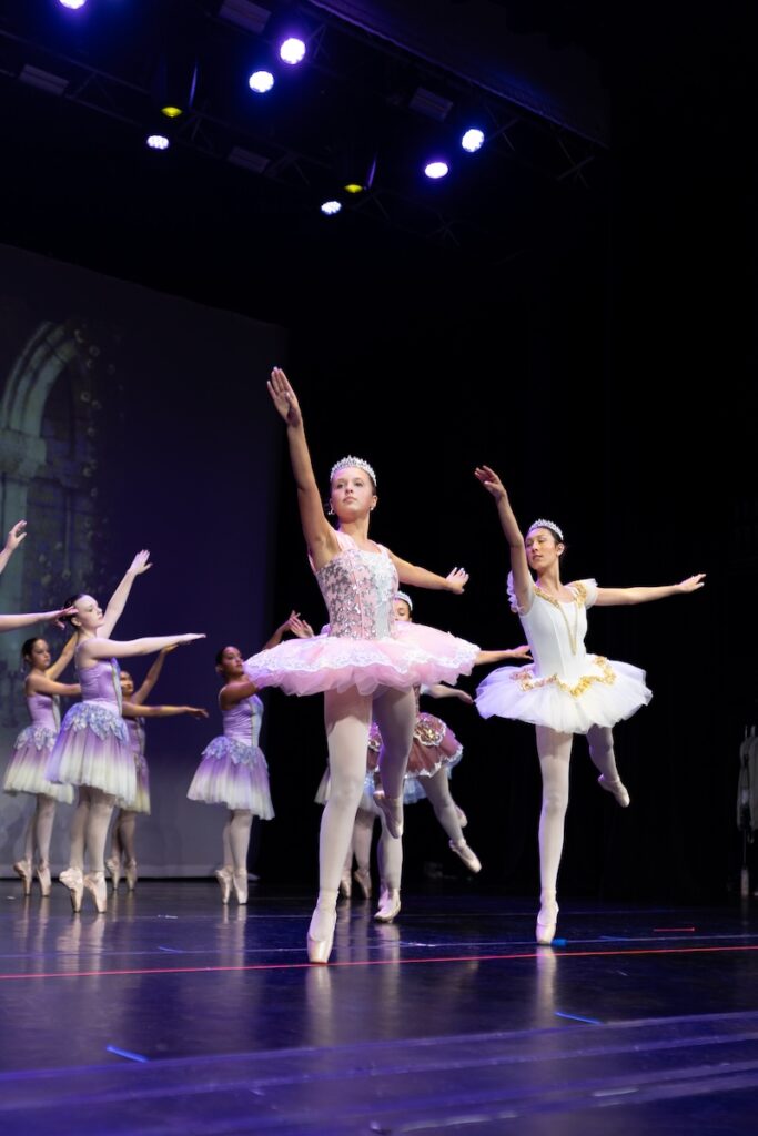 Young ballerinas performing on stage.