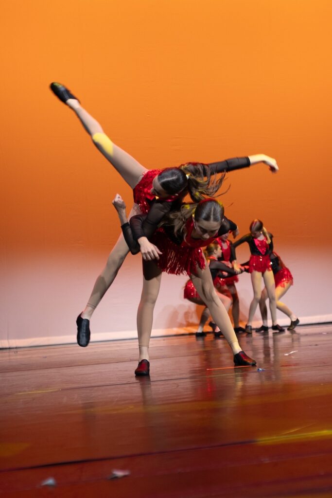 Jazz dancers performing tricks on stage.