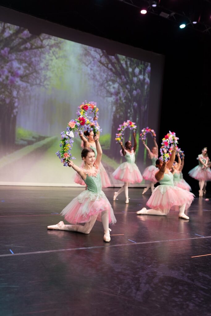Young ballerinas performing on stage.